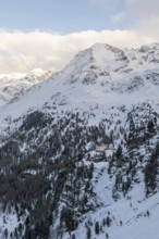 Mountain hut Zufallhütte in snowy mountain landscape, with mountain peak Vorderer Rotspitz,