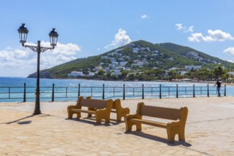 Large square at the harbour of Santa Eularia des Rui with lantern and benches, behind the peninsula