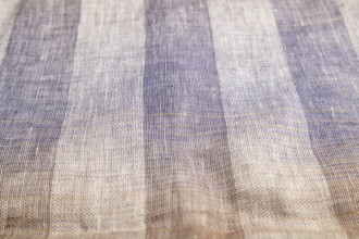 Fragment of smooth brown and violet linen tissue. Side view, natural textile background and texture