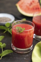 Watermelon juice with chia seeds and mint in glass on a black concrete background with green