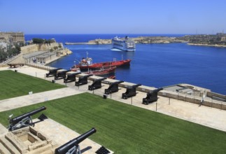 Merchant shipping and cruise ship arriving in Grand Harbour, Valletta, Malta from gun Saluting