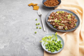 Quinoa porridge with green pea and chicken on ceramic plate on a gray concrete background and