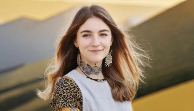 Smiling woman with tattoos and leopard print clothes in front of a dynamic yellow wall, AI