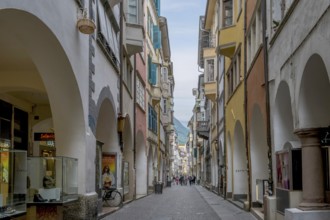 View through a lively pedestrian zone with arcades and shops, historic arcade in the old town