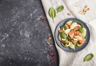 Fresh salmon with pineapple, spinach and cashew on a black concrete background. Top view, copy