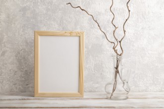 White wooden frame mockup with dried wine branch in glass on gray concrete background. Blank,