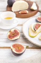 Summer appetizer with pear, cottage cheese, figs and honey on a white wooden background and linen