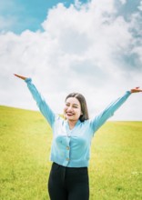 Happy young woman spreading arms in a beautiful field. Portrait of beautiful girl spreading arms