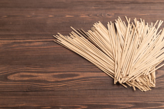 Japanese buckwheat soba noodles on brown wooden background. Side view, copy space