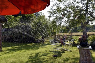 Europe, Germany, Lower Saxony, Stade district, garden in summer, garden table, water sprinkler,