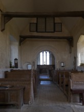 Norman chancel arch and wooden pews inside church of Saint John the Baptist, Wantisden, Suffolk,