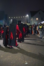 Group of people in black costumes takes part in a night procession, carnival, Schellbronn night