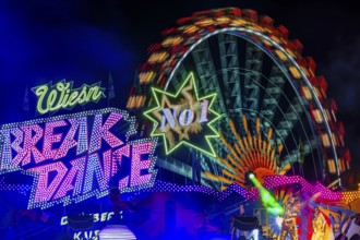 Illuminated ride Break Dance, behind the illuminated Ferris wheel in motion, night shot,