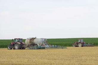 Farmers spread liquid manure on harvested grain field and plough it up, Swabian Alb,