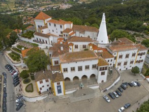 Aerial view of a historic castle with striking white towers and surrounding gardens, Royal Palace,