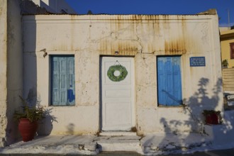 Traditional house with blue shutters and a white door with wreath, Pyles village, west coast,