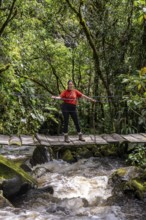 Young woman walking on suspension bridge along the Cocora Valley hiking trail, Cocora Valley,