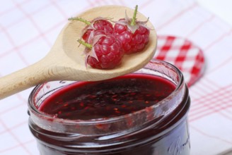 Raspberries (Rubus idaeus) on raspberry jam, raspberry jam, wooden spoon