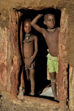 Himba children standing at the door of their hut, Omohanja, Kaokoland, Kunene, Namibia, Africa