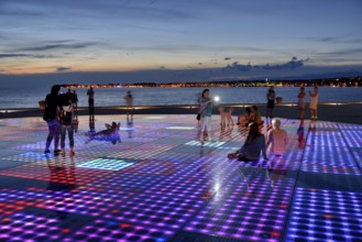 People at the Monument to the Sun, Pozdrav Suncu, by architect Nikole Bašica, at dusk, Zadar,