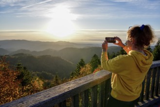 Woman photographing the sunset at Schliffkopf, near Baiersbronn, Freudenstadt district, Black