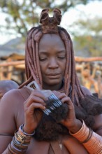 Himba woman combing her hair, Omuramba, Kaokoland, Kunene, Namibia, Africa