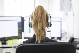 A woman wears headphones in an office in Berlin, 08.08.2024. Working in a call centre