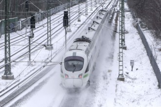 A Deutsche Bahn ICE train drives over snow-covered railway tracks and stirs up snow, Berlin,