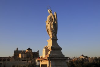 Angel San Rafael statue on Roman bridge Cordoba, Spain with view towards the cathedral