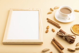 Composition with wooden frame, almonds, cinnamon and cup of coffee. mockup on orange background.