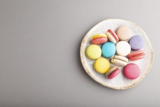 Multicolored macaroons on ceramic plate on gray pastel background. top view, copy space, still