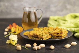 Traditional iranian dessert sohan with glass of green tea on a black concrete background and green