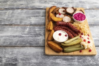 Set of snacks: sausages, toast, sauerkraut, marinated onion and cucumber, baked potato on a cutting