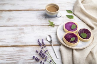 Sweet tartlets with jelly and milk cream with cup of coffee on a white wooden background and linen