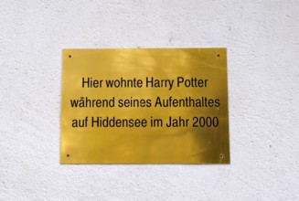 A golden plaque on a wall marking Harry Potter's stay in Hiddensee in 2000, joking sign, plaque on