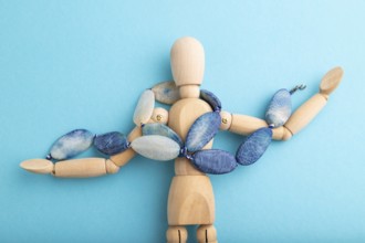 Wooden mannequin with blue agate beads on blue pastel background. copy space, isolated, luxury, bad