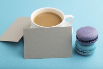 Gray paper business card mockup with blue and violet macaroons and cup of coffee on blue pastel