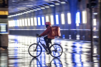 Street at the main station, Lieferando courier, cyclist, rainy weather, city centre, in the