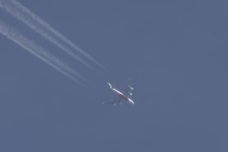 Airbus A380 aircraft of Emirates airlines flying across a blue sky leaving a contrail or vapor