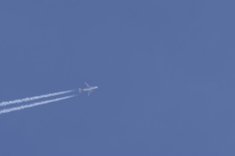 Airbus A320 aircraft of Easyjet airlines in flight with a contrail or vapour trail across a blue