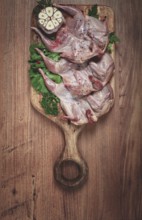 Raw quail meat, on a cutting board, with spices and herbs, top view