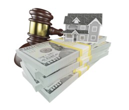 Miniature house with stack of money and wooden gavel isolated on a white background