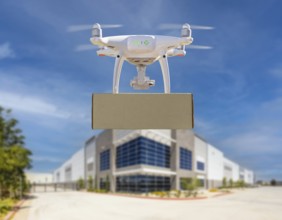 Unmanned aircraft system (UAS) quadcopter drone carrying blank package near corporate commercial