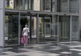 Senior citizen with walking stick at the exit of a building, Berlin, Germany, Europe