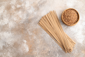 Japanese buckwheat soba noodles with tomato, eggs, spices, herbs on brown concrete background. Top