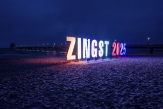 Colourful letters form the lettering Zingst 2025, with the pier of the Baltic seaside resort of