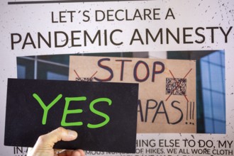 Symbolic image of Pandemic Amnesty: a section of a symbolic newspaper with a sign reading YES held