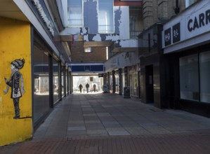 People walking along walkway beneath former Co-op department store building, Ipswich, Suffolk,