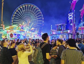 People at the Cranger Kirmes in the evening in front of the Ferris wheel, Herne, Ruhr area, North