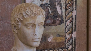 Classical portrait of an ancient marble bust, head of a young man, against a mosaic background,